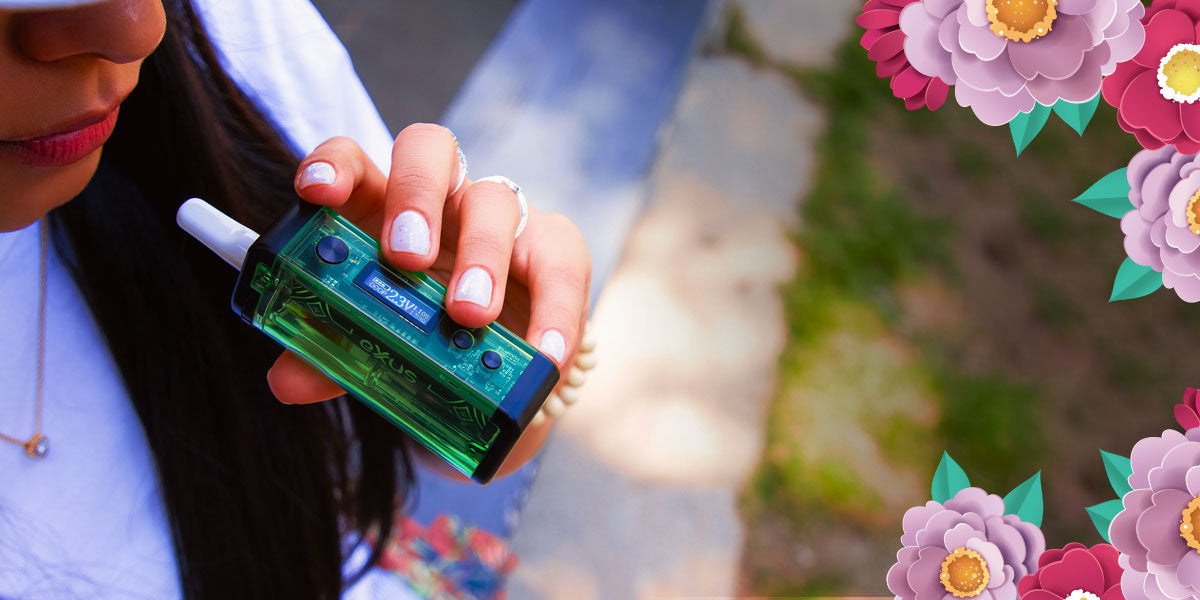 woman with hat holding the Exxus Adapt vaporizer with flowers
